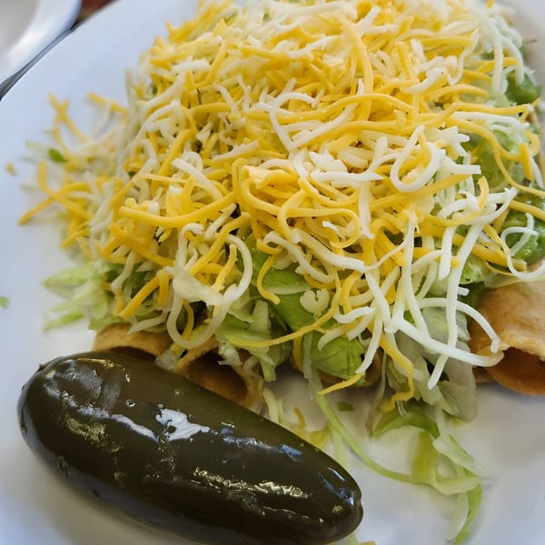 Los Amigos Mexican food with shredded cheese, lettuce, and a large pickled jalapeño.