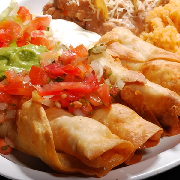 Los Amigos Mexican taquitos with guacamole, pico de gallo, sour cream, rice, and beans.