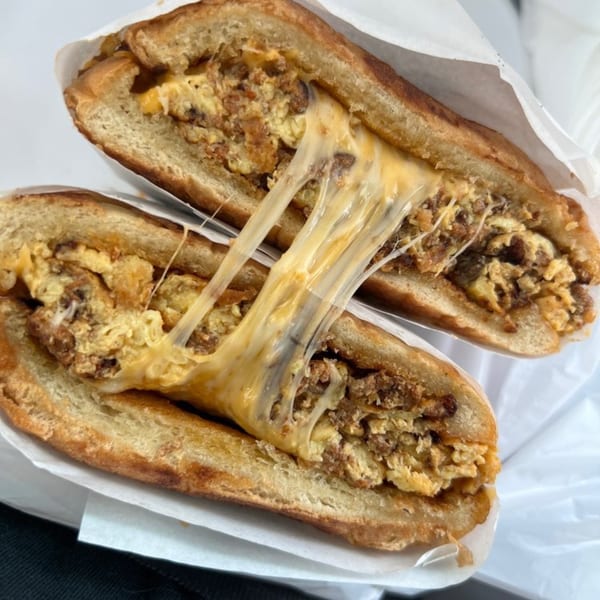 A Los Amigos Mexican food sandwich, cut in half, with melted cheese stretching between the halves.